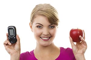 Happy woman holding glucometer and fresh apple.
